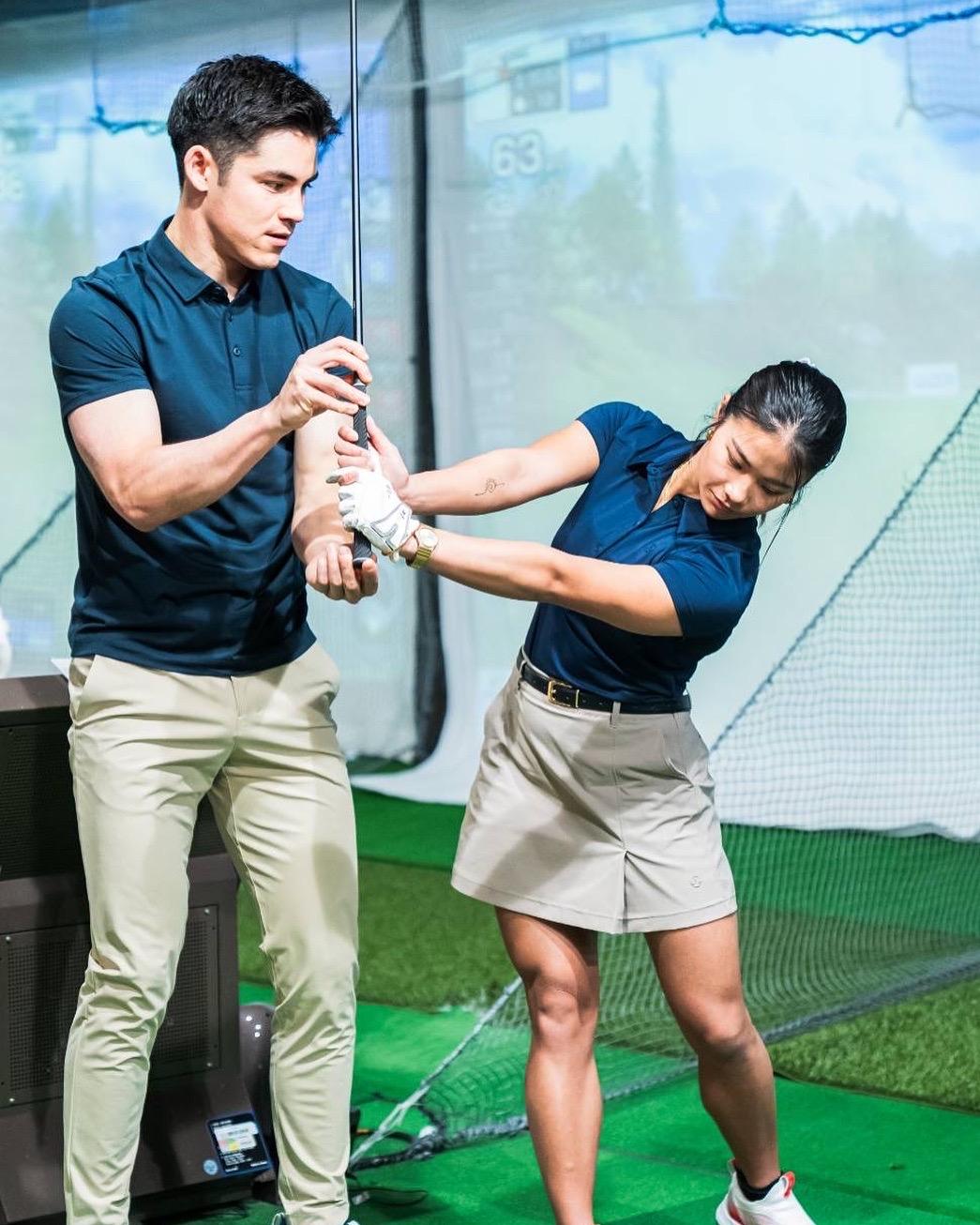 Louis coaching a student in an indoor golf simulator